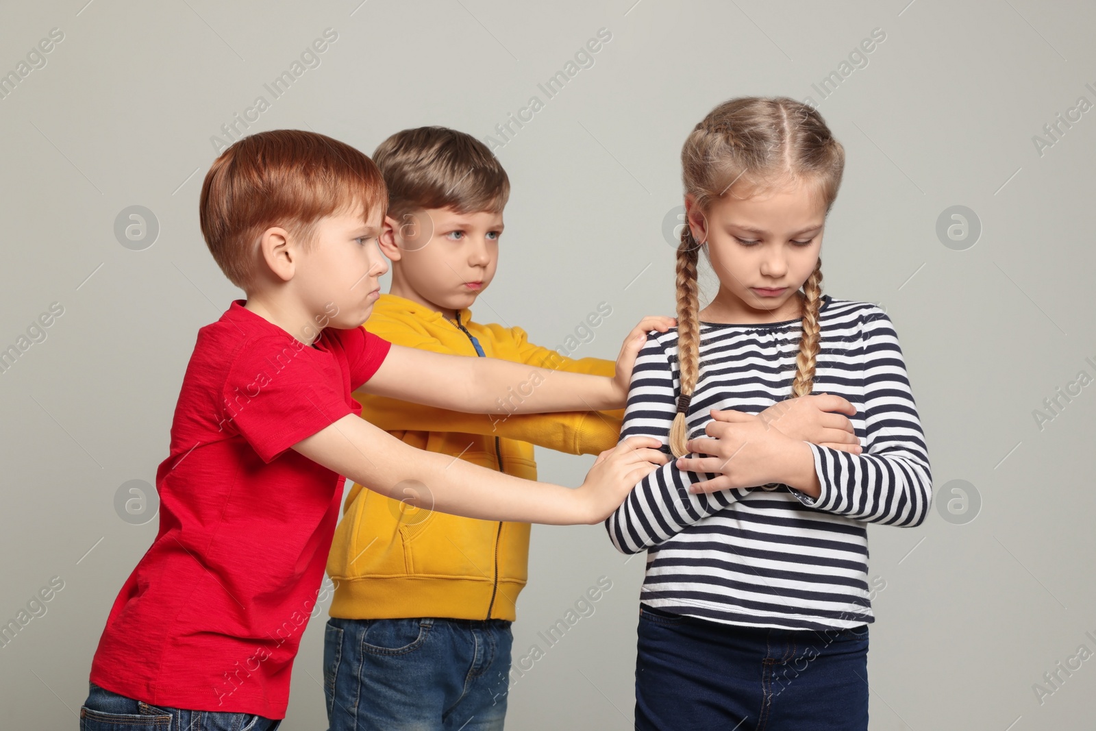 Photo of Boys bullying girl on light grey background