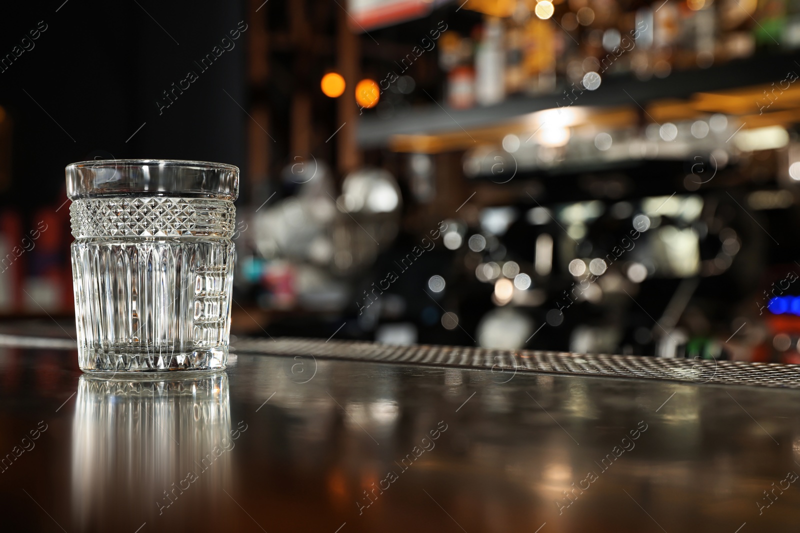 Photo of Empty clean glass on counter in modern bar. Space for text