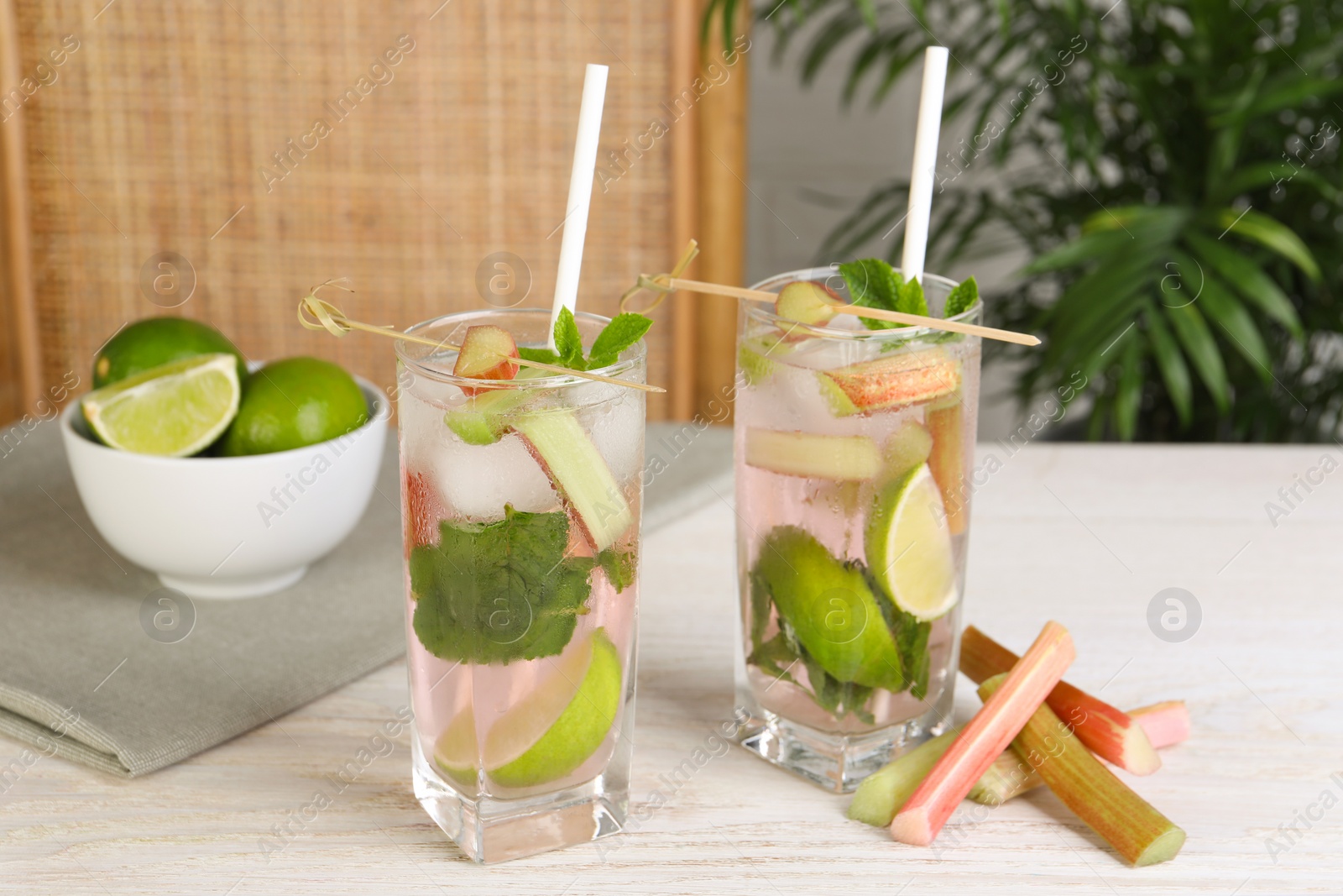 Photo of Tasty rhubarb cocktail with lime on white wooden table indoors