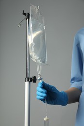 Photo of Nurse with IV infusion set on grey background, closeup