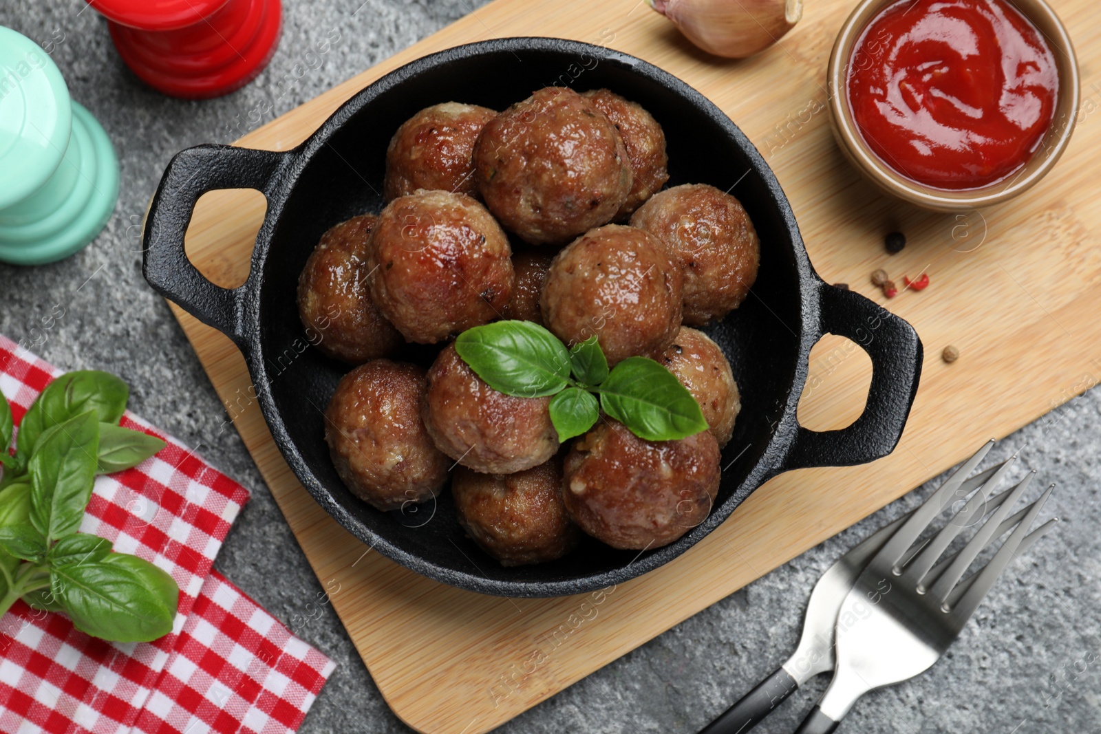 Photo of Tasty cooked meatballs with basil served on grey table, flat lay