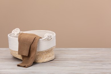 Wicker laundry basket with clothes near beige wall. Space for text