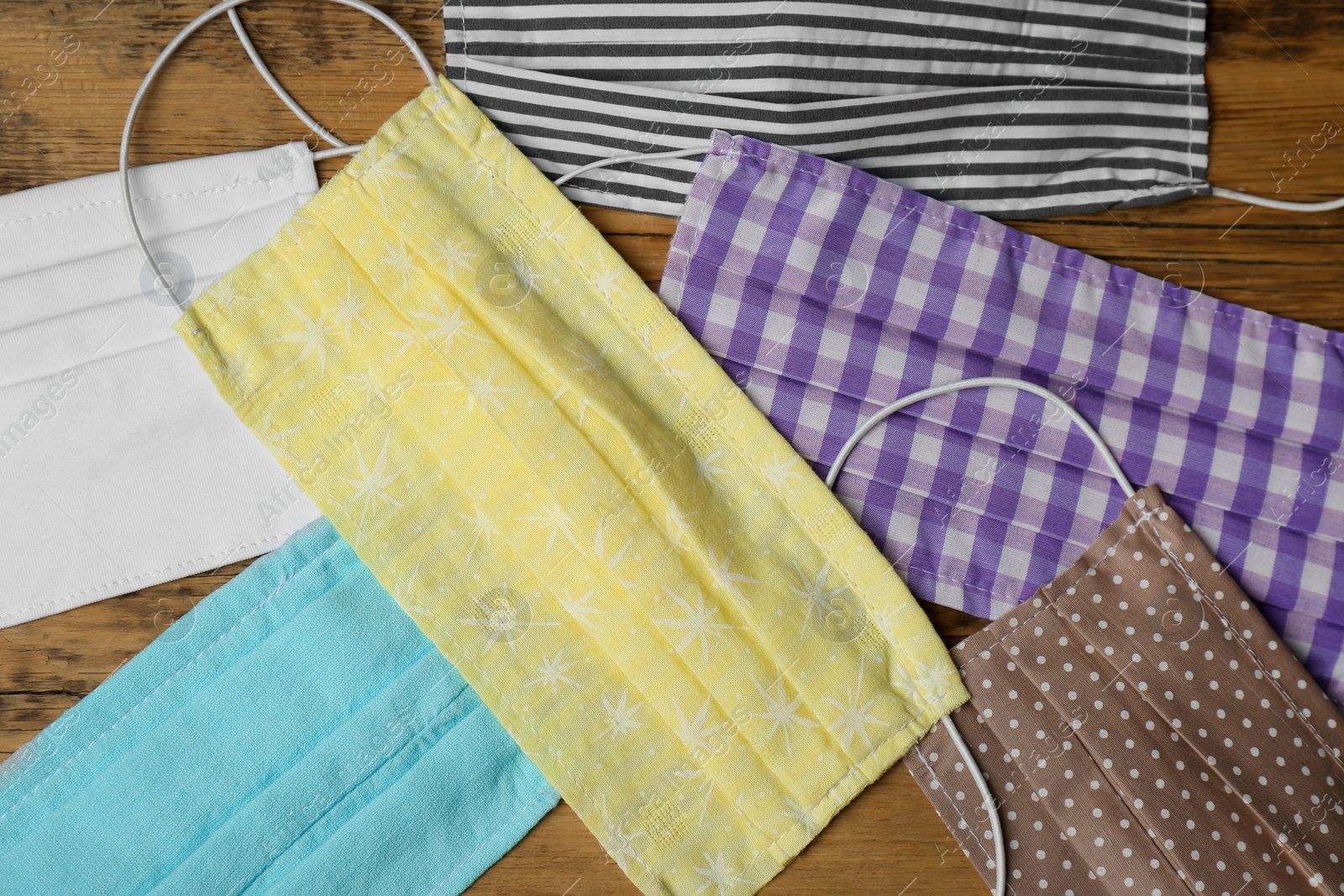 Photo of Homemade protective face masks on wooden table, flat lay