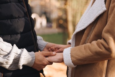 Happy young couple holding hands together outdoors, closeup. Dating agency