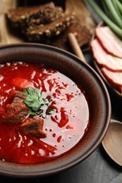 Stylish brown clay bowl with Ukrainian borsch served on black table, closeup