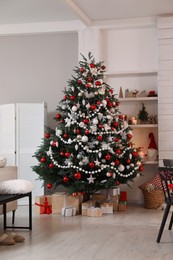 Photo of Beautifully decorated Christmas tree and gift boxes in room. Interior design