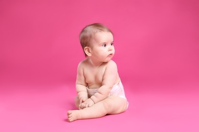 Photo of Cute little baby in diaper sitting on pink background