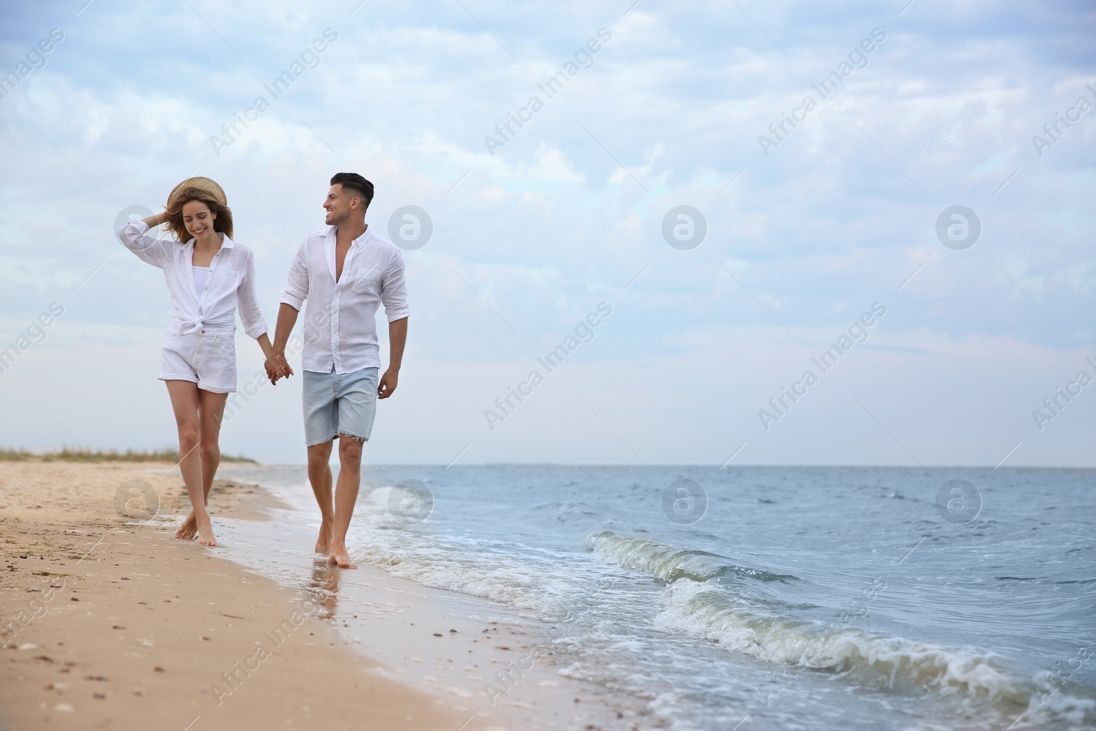 Photo of Happy couple having romantic walk on beach. Space for text