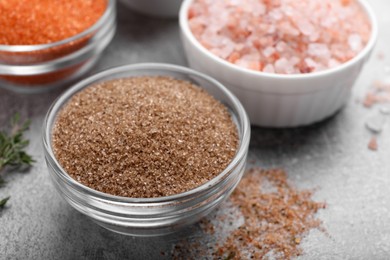 Photo of Different kinds of salt on grey table, closeup