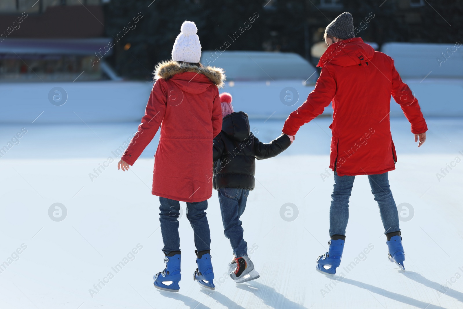 Image of Family spending time together at outdoor ice skating rink, back view