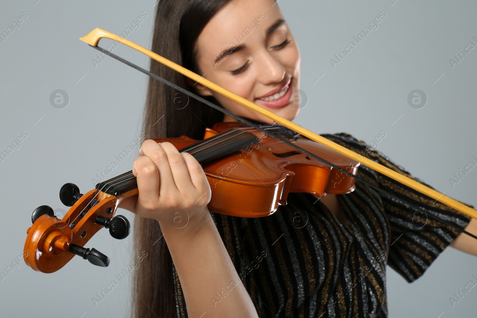 Photo of Beautiful woman playing violin on grey background, closeup