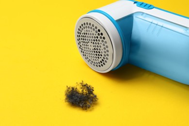 Modern fabric shaver and lint on yellow background, closeup