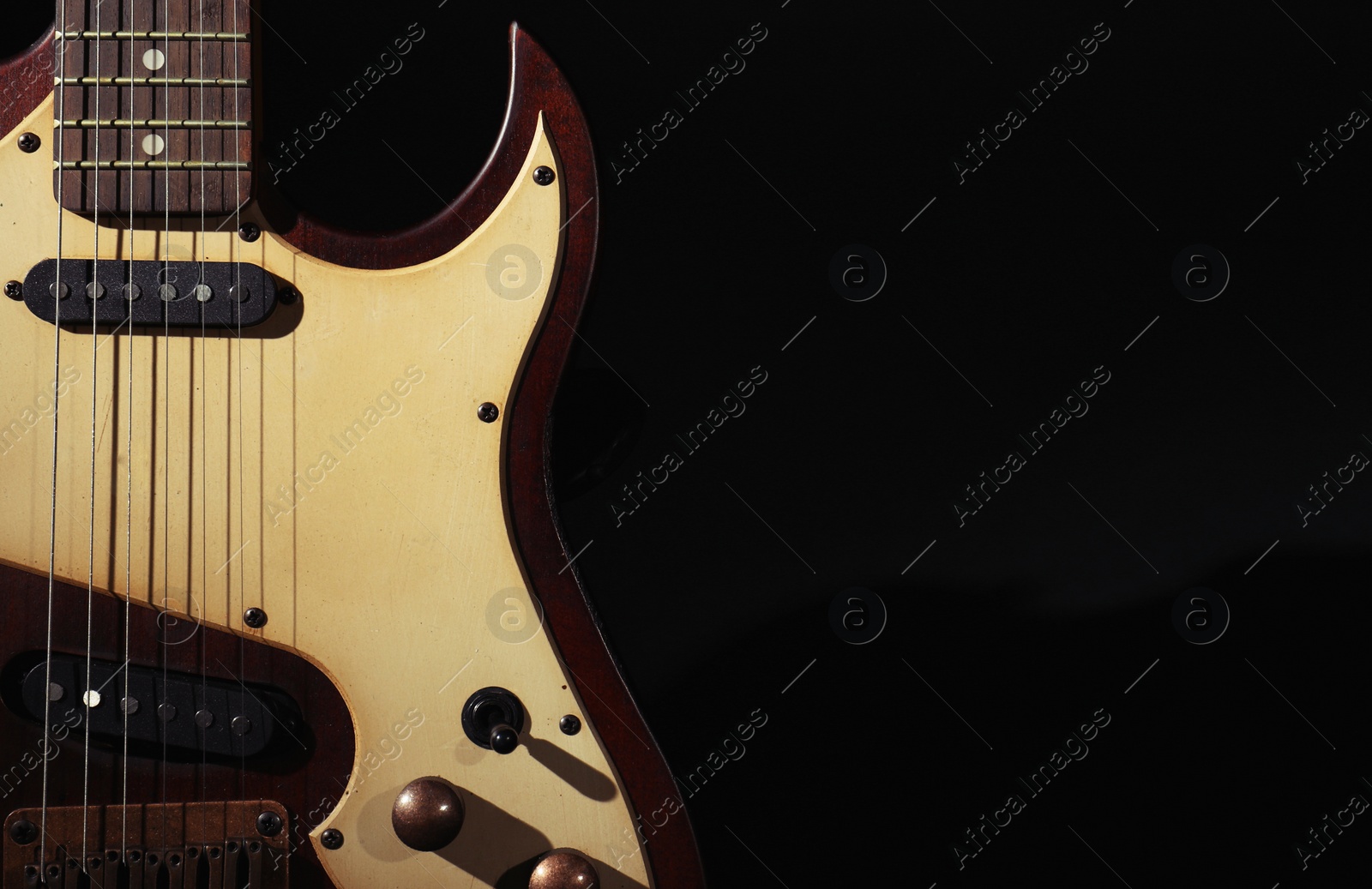 Photo of Electric guitar on black background. Space for text