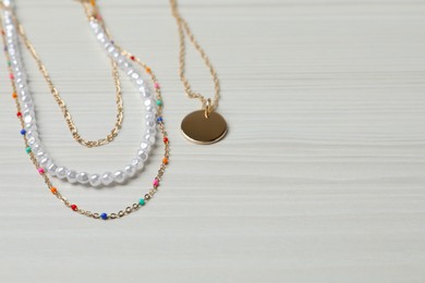 Photo of Necklaces on white wooden table, closeup. Space for text