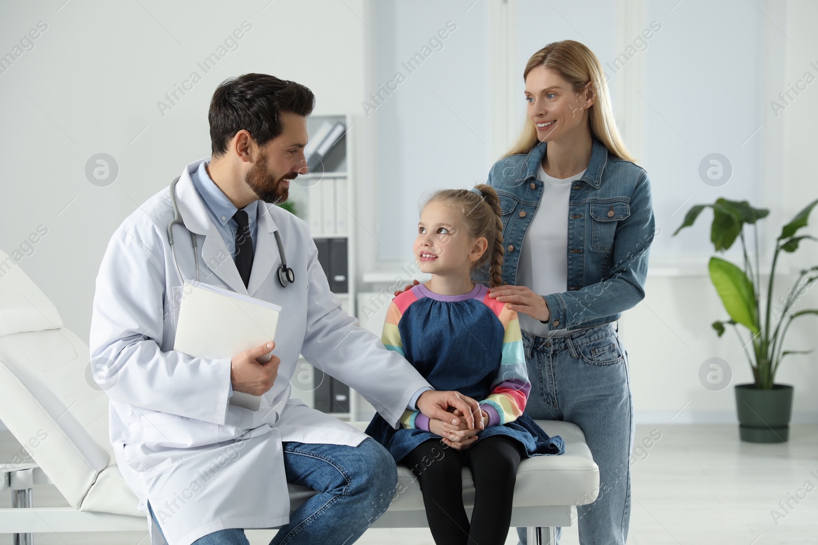 Photo of Happy mother and daughter having appointment with doctor. Pediatrician consulting patient in clinic