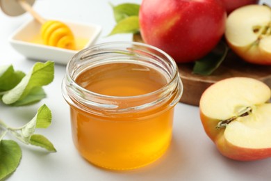 Photo of Sweet honey and fresh apples on white table, closeup