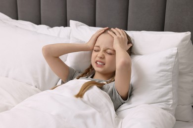 Little girl suffering from headache in bed