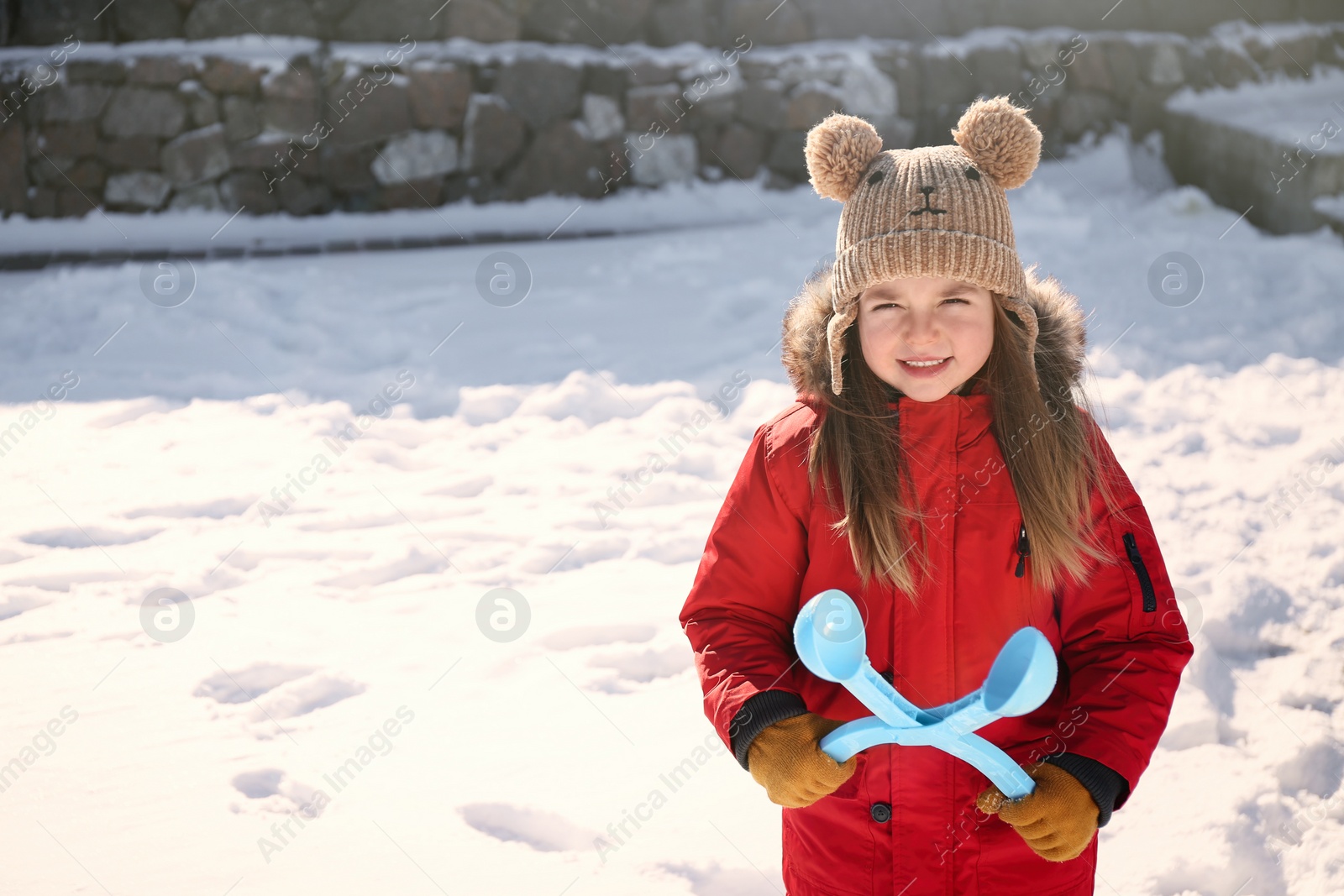 Photo of Cute little girl playing with snowball maker outdoors