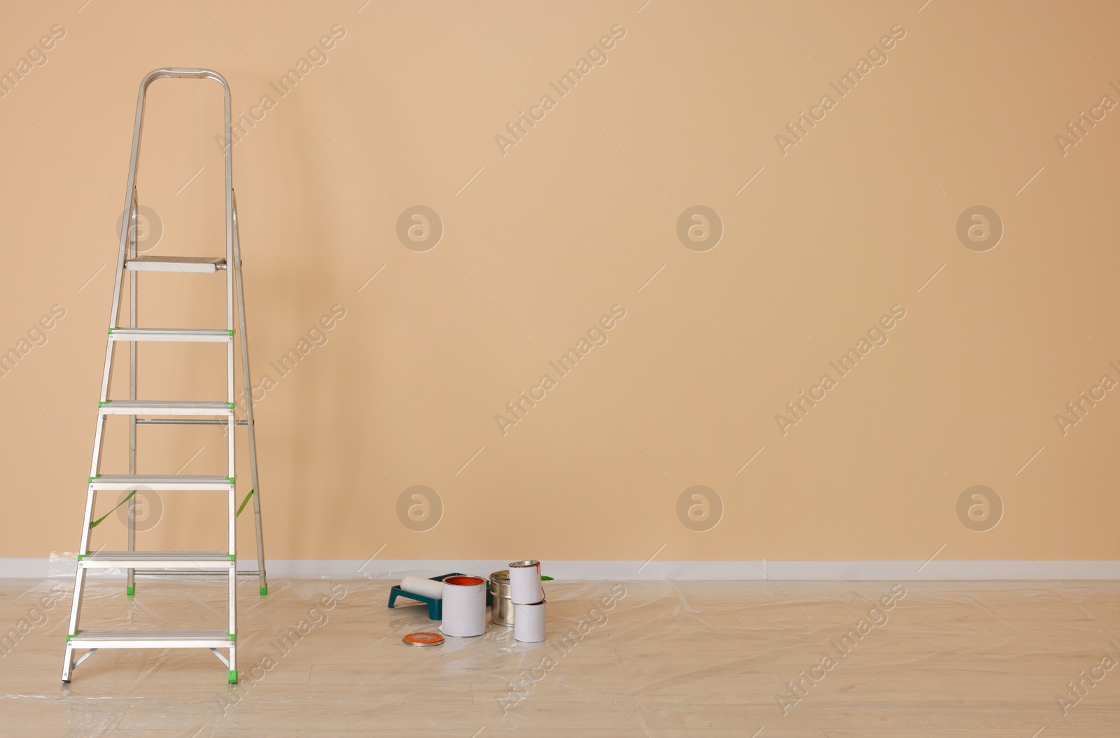 Photo of Metal stepladder near pale orange wall indoors, space for text. Room renovation