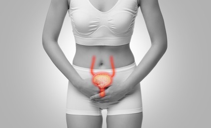 Woman suffering from cystitis on light grey background, closeup. Illustration of urinary system