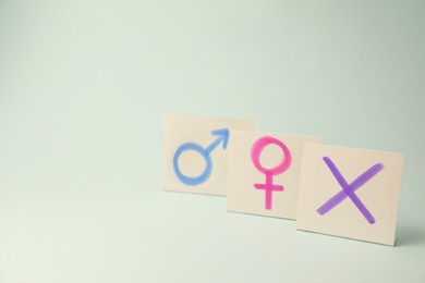 Photo of Gender identity concept. Cards with cross mark and gender symbols on light background, space for text