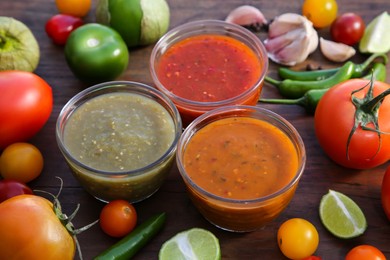 Tasty salsa sauces and ingredients on wooden table, closeup