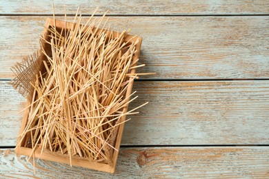Photo of Dried hay in crate on light wooden background, top view. Space for text