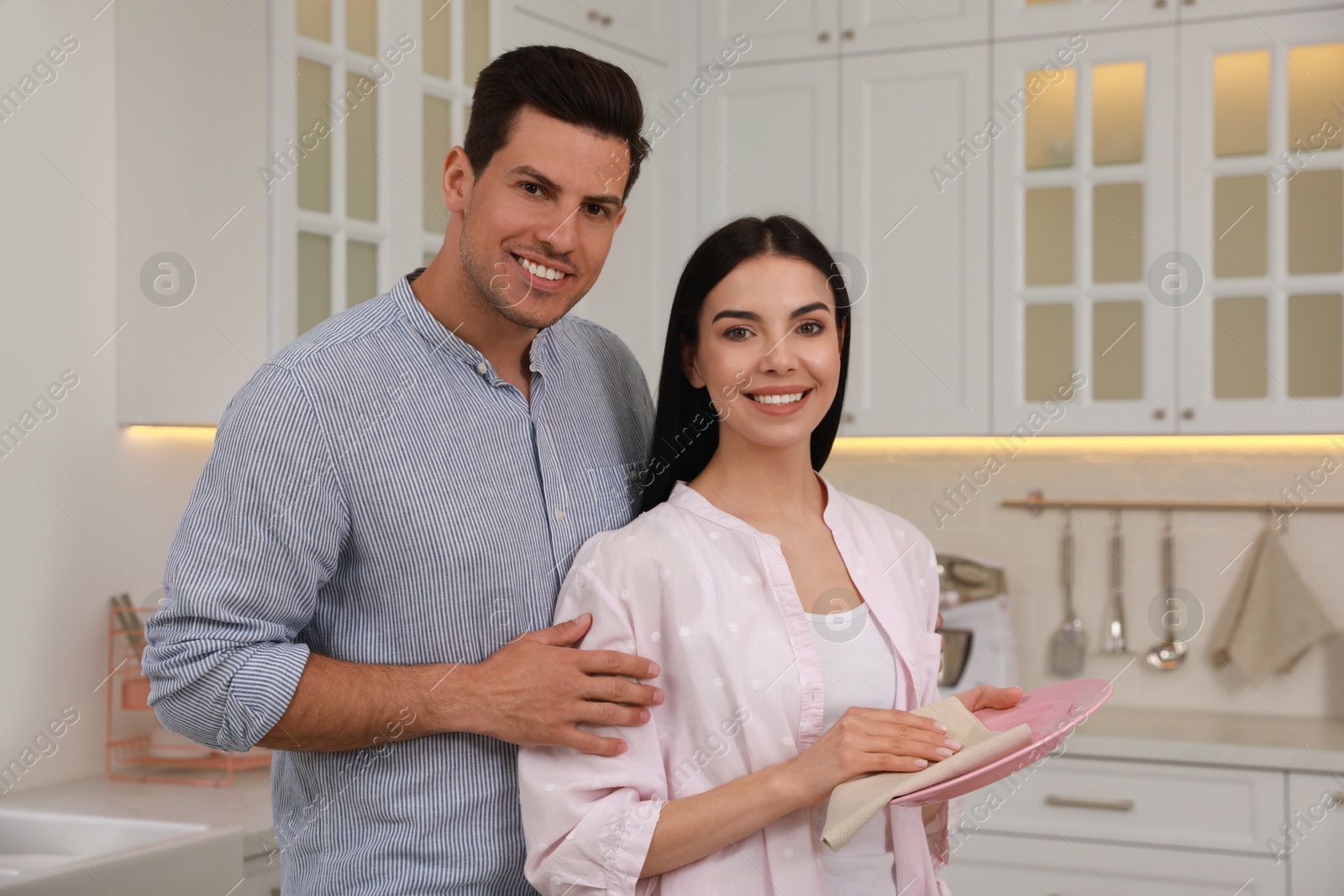 Photo of Happy couple with clean dishes in kitchen