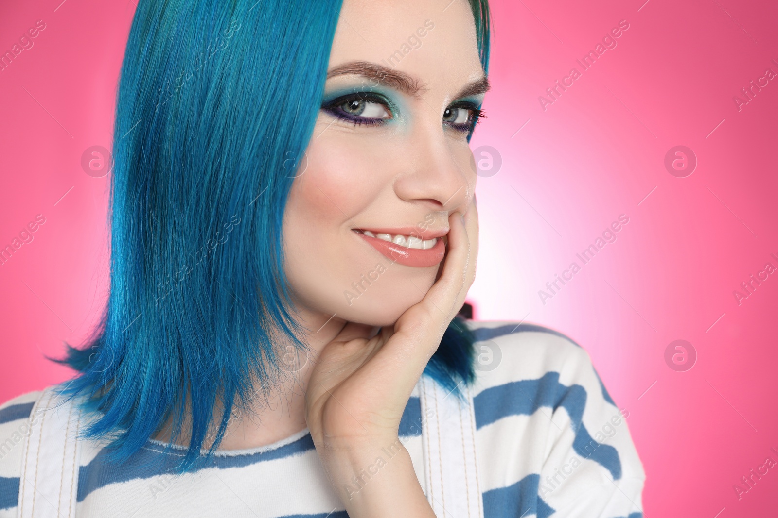 Photo of Young woman with bright dyed hair on pink background, closeup