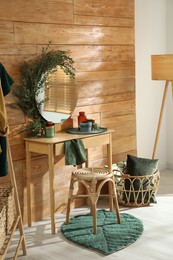 Photo of Stylish dressing table and mirror decorated with green eucalyptus in room