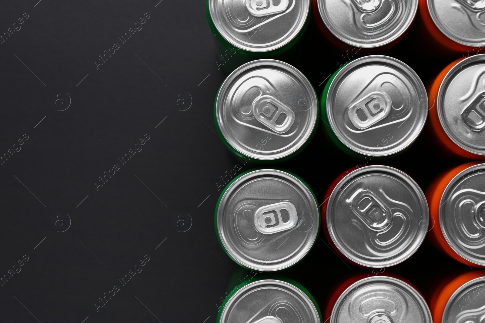 Photo of Energy drink in cans on black background, top view. Space for text