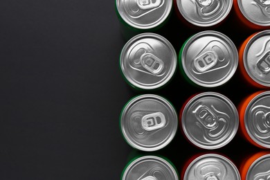 Energy drink in cans on black background, top view. Space for text