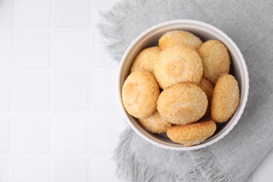 Photo of Tasty sugar cookies in bowl on white tiled table, top view. Space for text