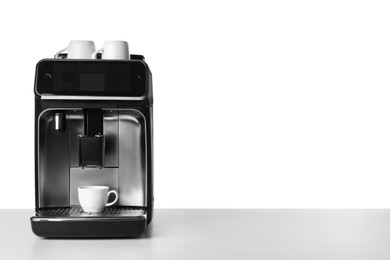 Photo of Modern electric coffee machine with cups on table against white background. Space for text