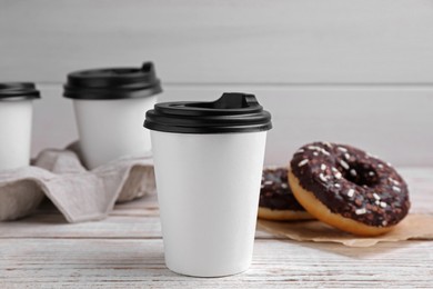 Photo of Cups of hot drinks and tasty donuts on white wooden table