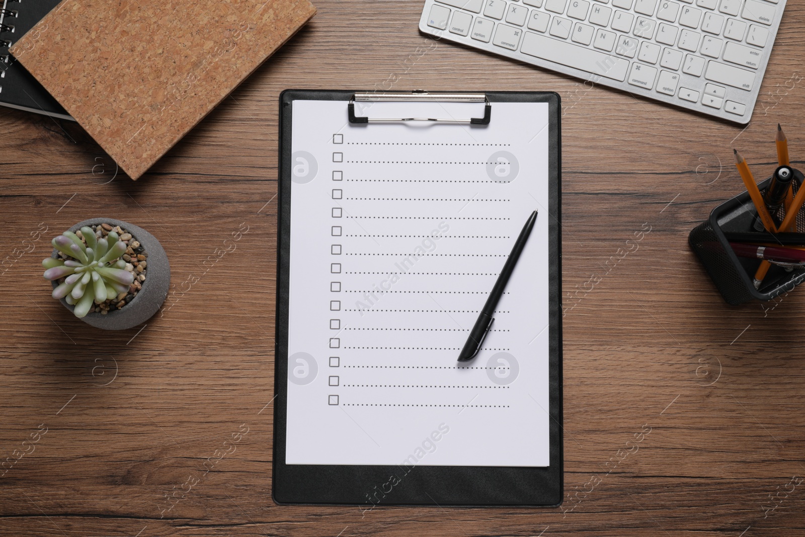 Photo of Clipboard with checkboxes, computer keyboard and plant on wooden table, flat lay. Checklist