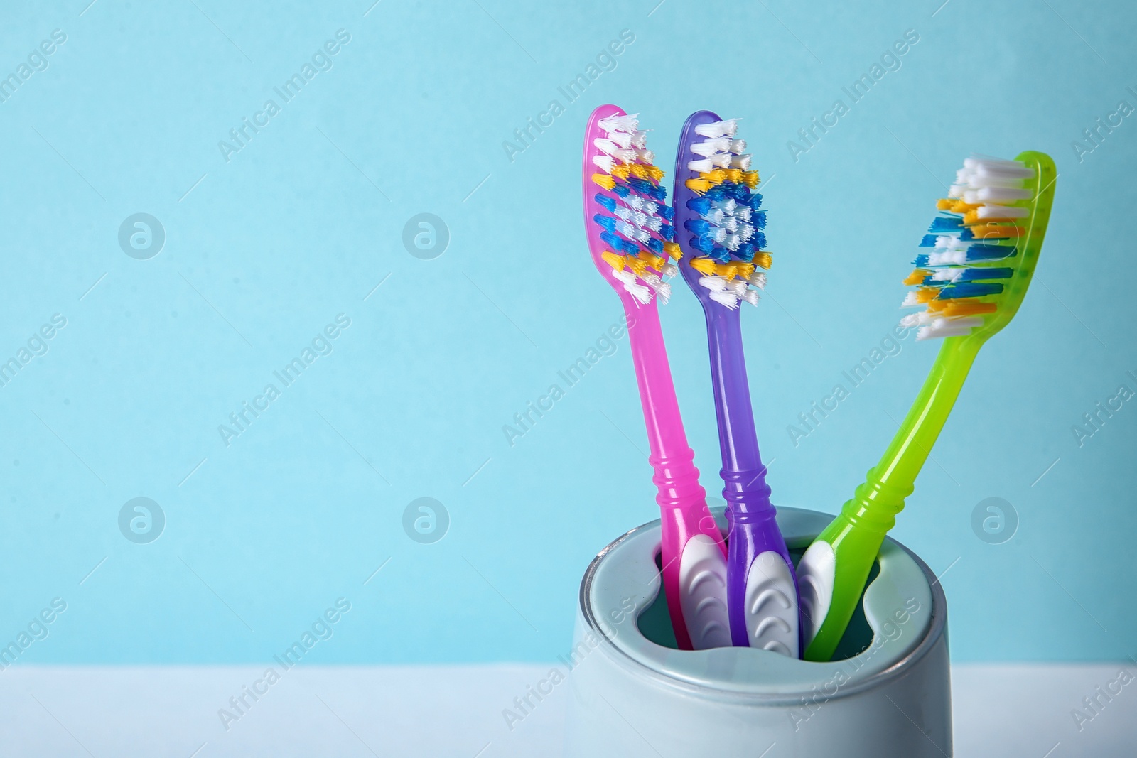 Photo of Cup with toothbrushes against color background, closeup