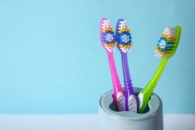 Photo of Cup with toothbrushes against color background, closeup