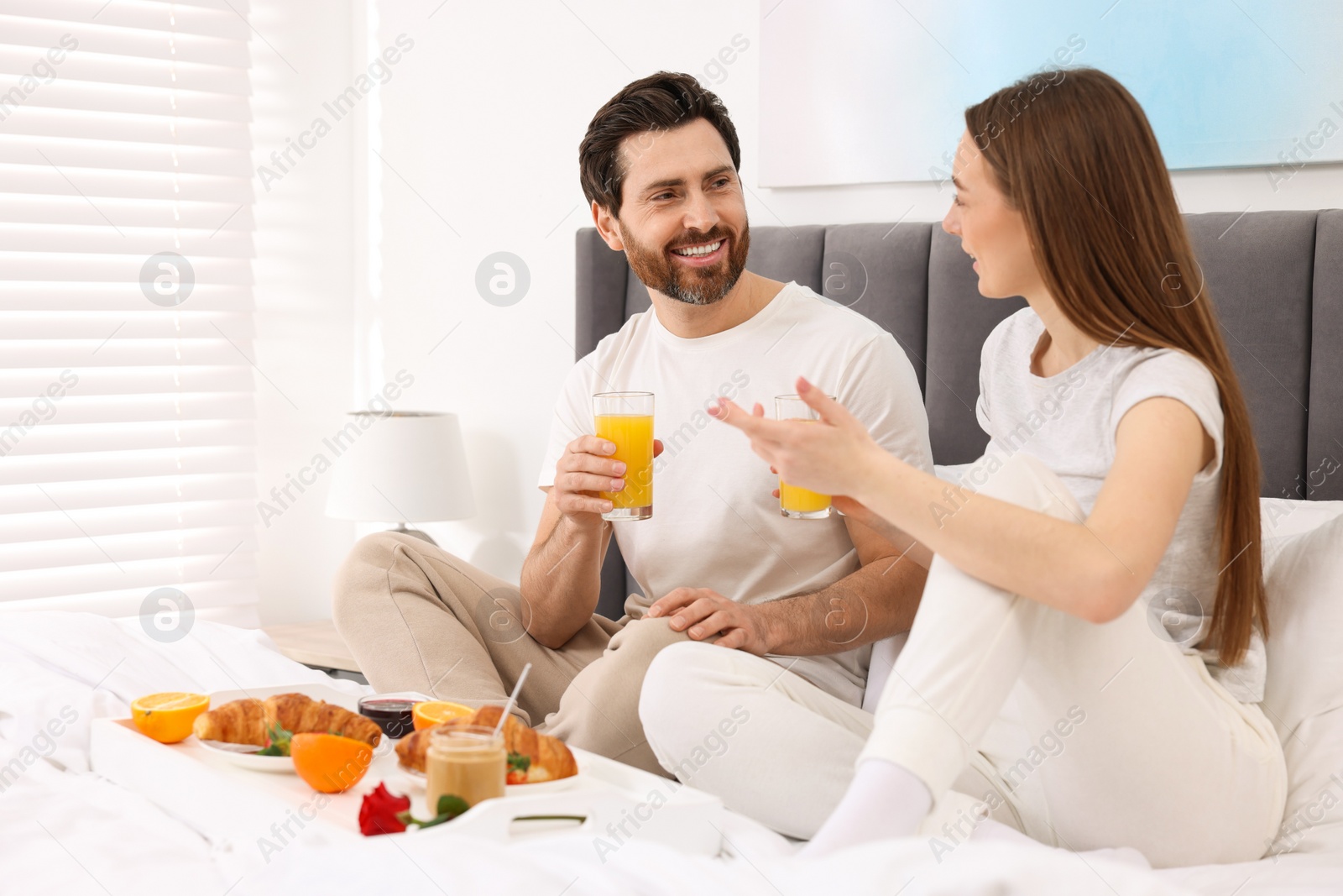 Photo of Happy couple having breakfast and talking in bedroom. Space for text