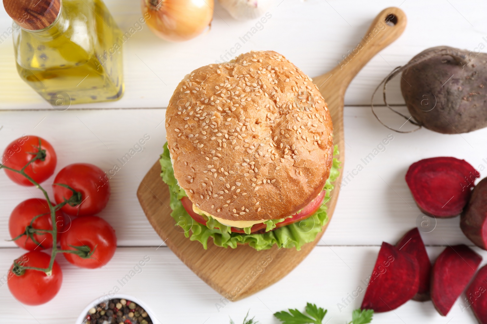 Photo of Delicious vegetarian burger and ingredients on white wooden table, flat lay