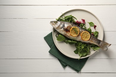 Photo of Baked fish with spinach and lemon on white wooden table, top view. Space for text