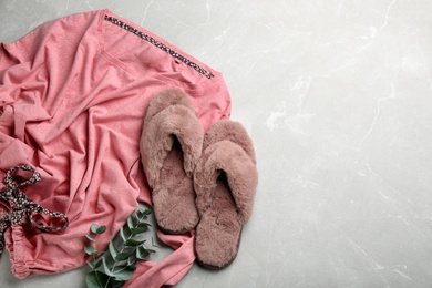 Photo of Pair of fluffy slippers, pajamas and space for text on grey background, flat lay. Comfortable home outfit