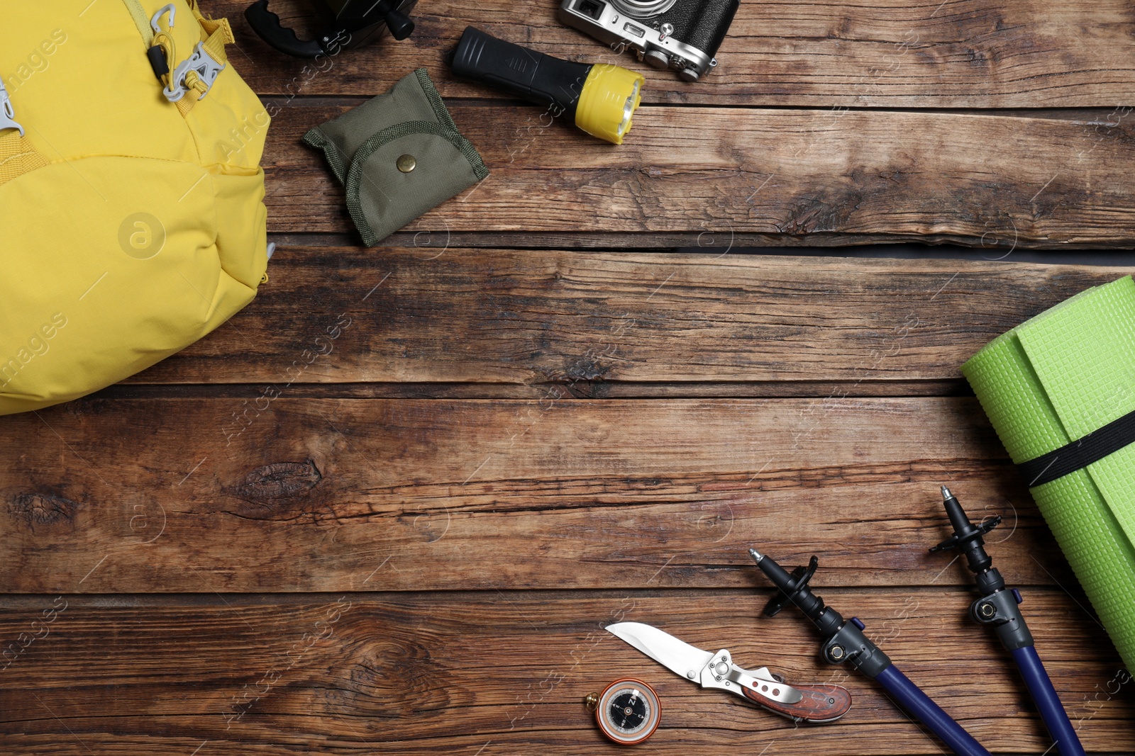 Photo of Flat lay composition with tourist backpack and other camping equipment on wooden background, space for text