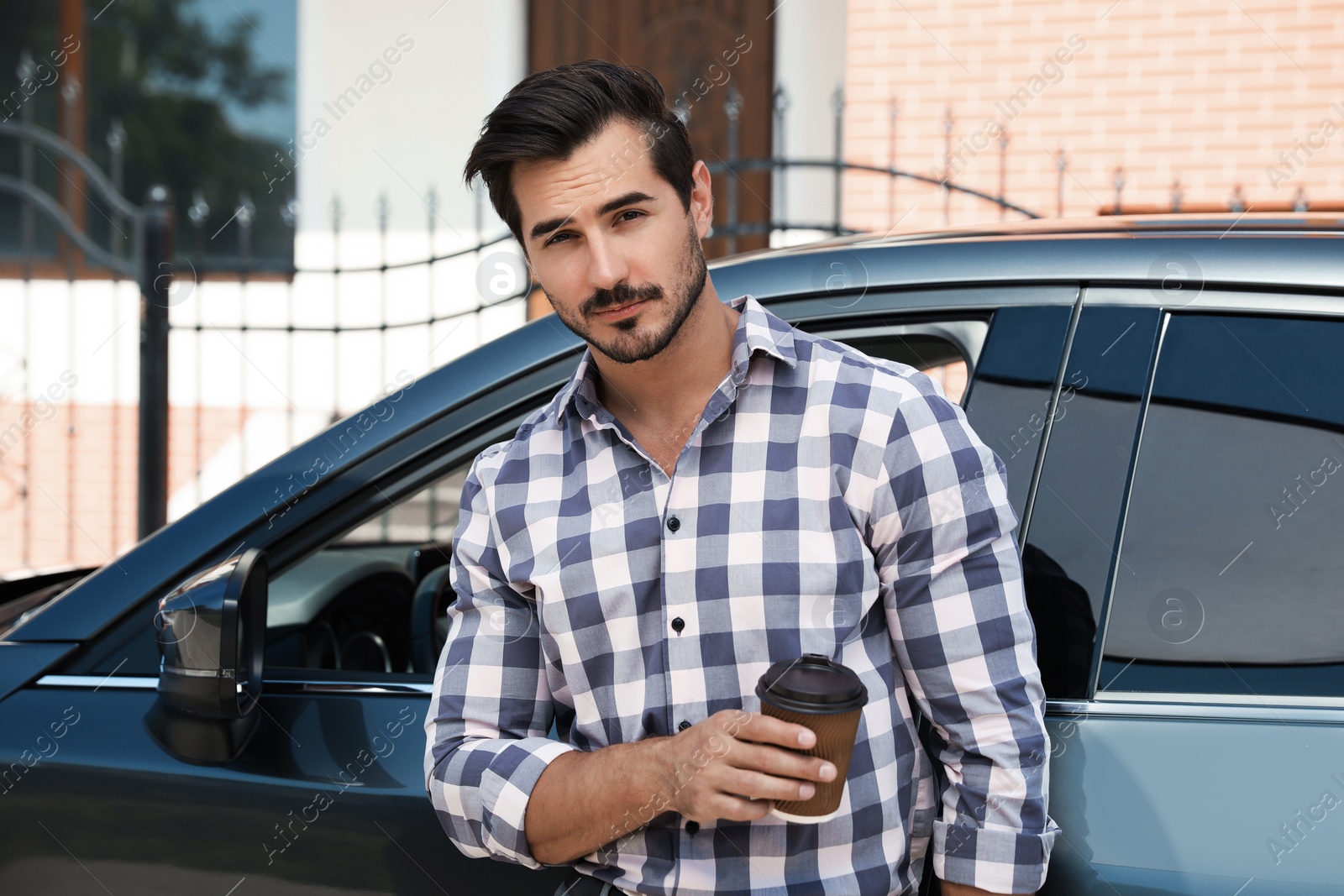 Photo of Attractive young man with cup of coffee near luxury car outdoors