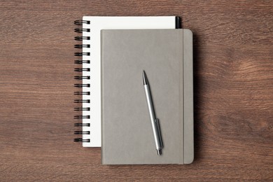 Photo of Stylish notebooks and pen on wooden table, top view