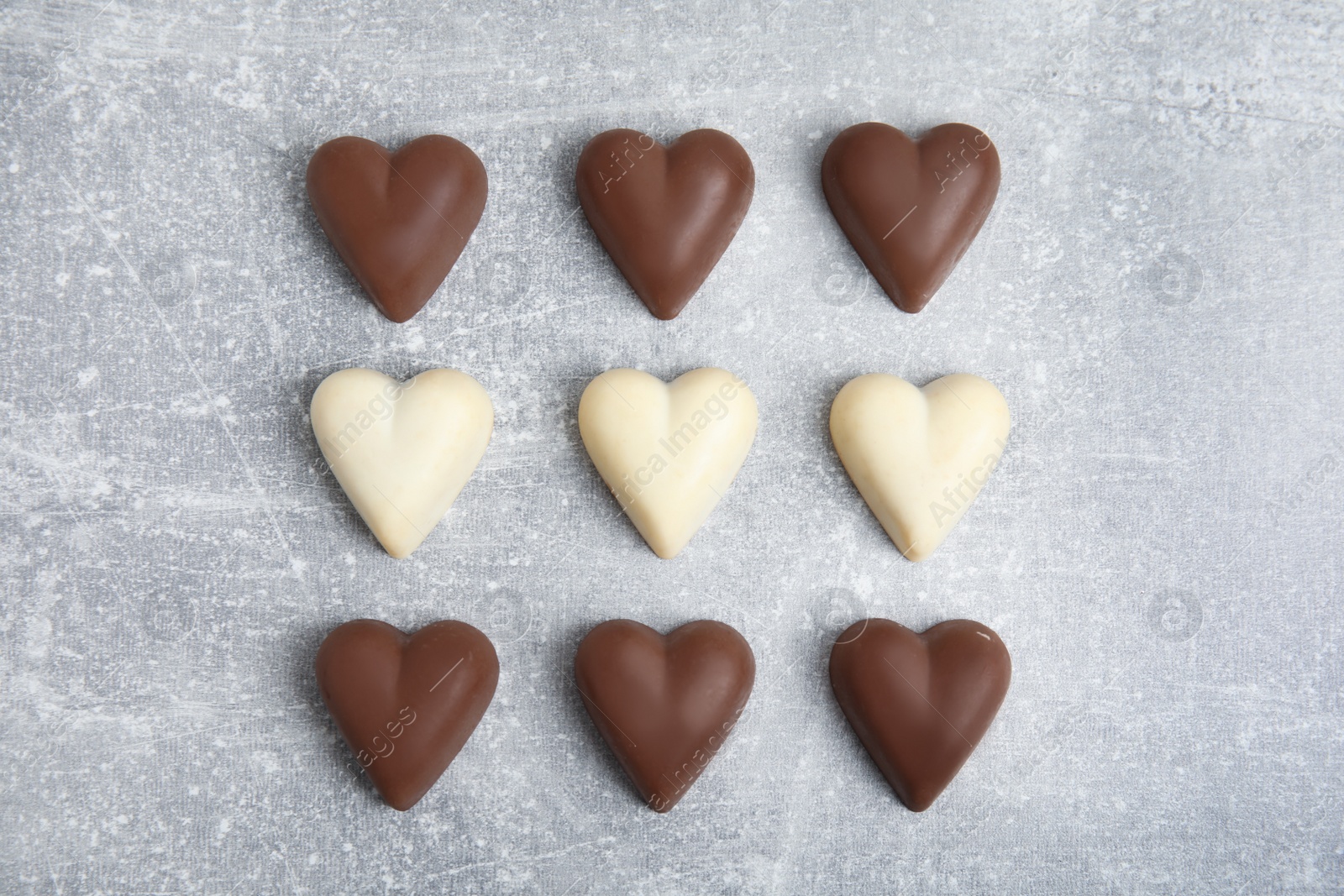 Photo of Tasty heart shaped chocolate candies on light grey table, flat lay. Happy Valentine's day