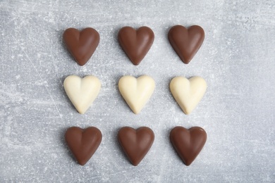 Tasty heart shaped chocolate candies on light grey table, flat lay. Happy Valentine's day