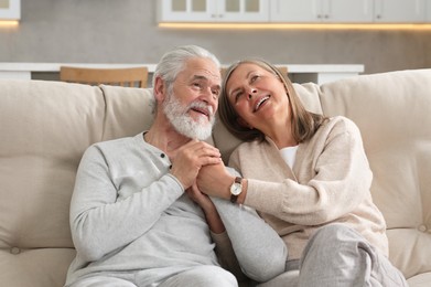 Photo of Affectionate senior couple relaxing on sofa at home