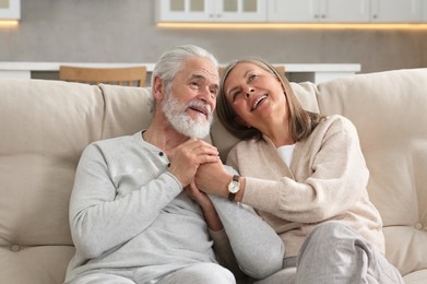 Affectionate senior couple relaxing on sofa at home