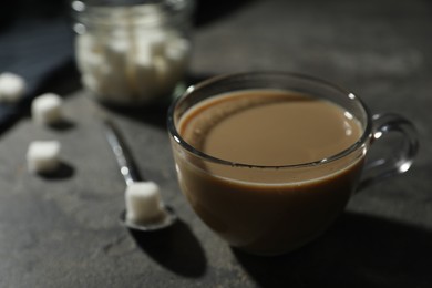 Photo of Tasty coffee with milk in cup and sugar cubes on grey table, closeup